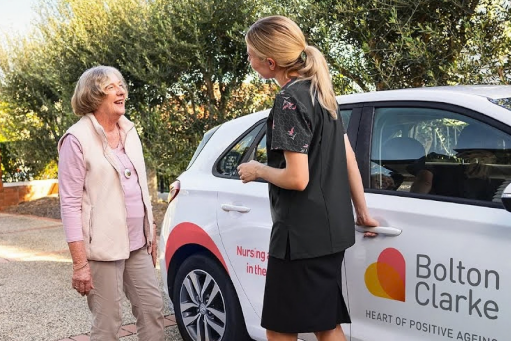 photo of an elderly lady talking a young woman infront of a car